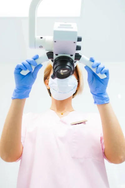 Kvinnliga tandläkare undersöker dental Mikroskop. Underifrån. Fokusera på läkaren — Stockfoto
