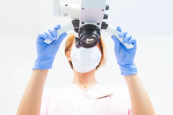 Une dentiste examine un microscope dentaire. Vue du bas. Focus sur le médecin — Photo
