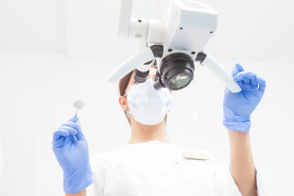 Bir kadın dişçi diş mikroskop bakıyor. Alt görünümü. Doktor üzerinde odaklanmak — Stok fotoğraf