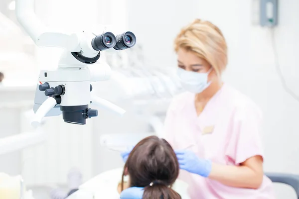 Microscopio binocular endodóntico dental profesional en la sala de tratamiento. En el contexto de una dentista y una paciente. Centrándose en un microscopio — Foto de Stock