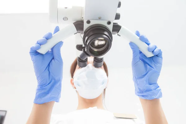 Una dentista está mirando dentro de un microscopio dental. Vista de abajo. Enfoque en el microscopio — Foto de Stock