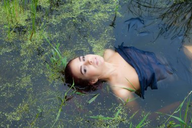 bir siyah bezle örtülü bir bataklık içinde genç bir kadın yatıyor