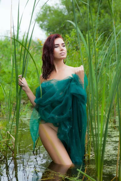緑の布で覆われて、沼に若い女性が立っています。 — ストック写真