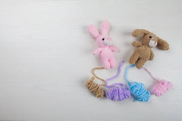 Knitted toys - a rabbit and a dog are lying on the board. colored thread — Stock Photo, Image