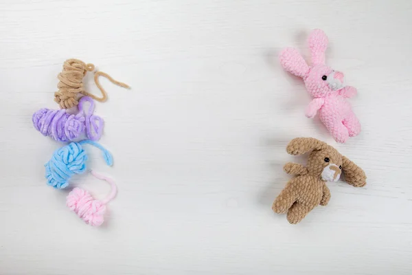 Brinquedos tricotados - um coelho e um cão estão deitados no tabuleiro. linha colorida — Fotografia de Stock