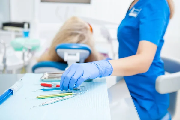 A close-up photo of a dentist's hand taking a sterile instrument from a metal tray. Focus on the doctor's hand — Stock Photo, Image