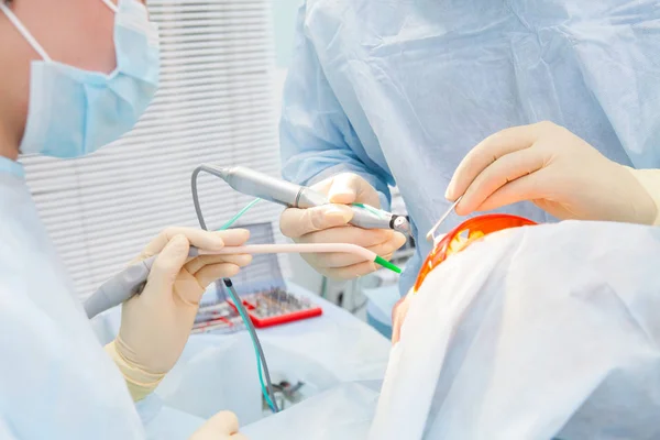 Close-up process of male professional dentist surgeon performing operation install dental implant teeth of man patient in clinic. — Stock Photo, Image