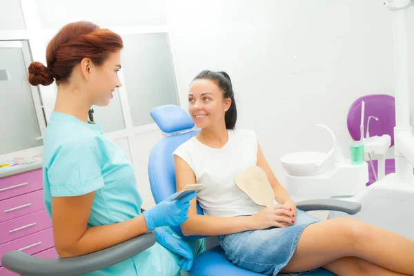 Dentista se comunica con una paciente en la sala de tratamiento —  Fotos de Stock