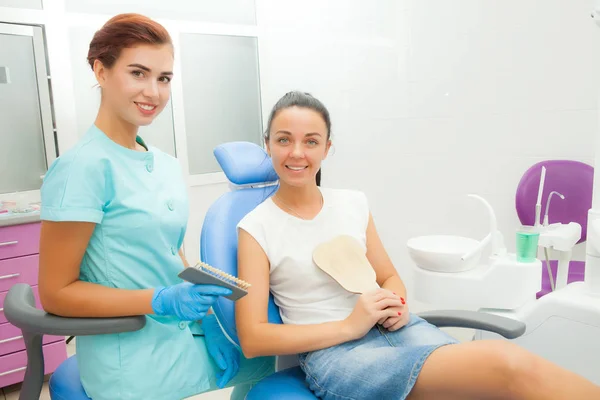 Hermosa paciente femenina con tratamiento dental en el consultorio del dentista. Una mujer visitando a su dentista. Las mujeres miran a la cámara —  Fotos de Stock