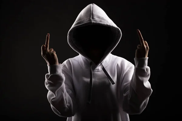 Silhouette of a man in a hood on a black background, the face is not visible. shows hands gesture fuck — Stock Photo, Image