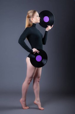 Güzel bir kız iki vinil diskler, uzağa bakıyor tutuyor. Stüdyo gri bir arka plan üzerine vurdu. Profilde anlık görüntü