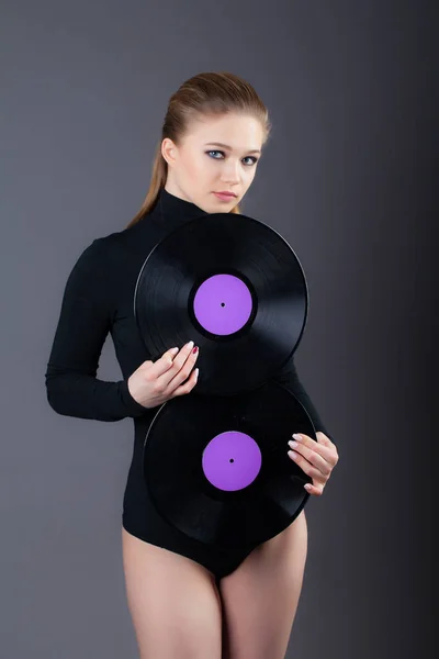 Красива дівчина тримає два вінілові диски. Студійний знімок на сірому фоні . — стокове фото