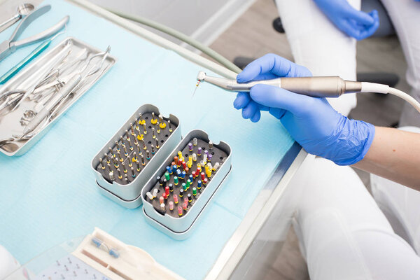 Closeup picture of dental instruments: drill and needle for root canal treatment and pulpitis in hand at the dentist