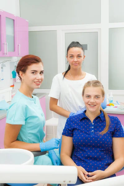 Zubní lékař ortodontista s pacientem a asistent dívat do kamery. Zubní ošetření v operační místnosti. — Stock fotografie