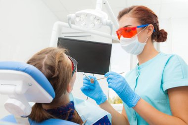 Genç kadın - ortodontist dişçi diş kliniği diş sandalyede içinde yatan hastanın diş davranır. Hasta genç kadın