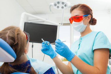 Genç kadın - ortodontist dişçi diş kliniği diş sandalyede içinde yatan hastanın diş davranır. Hasta genç kadın