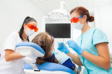 Genç bir kadın bir dişçi ortodontist ve bir kadın Yardımcısı bir hastanın diş diş kliniğinde diş bir sandalyede yalan davranır. Bir genç kadın hasta