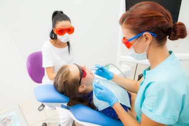 Genç bir kadın bir dişçi ortodontist ve bir kadın Yardımcısı bir hastanın diş diş kliniğinde diş bir sandalyede yalan davranır. Bir genç kadın hasta