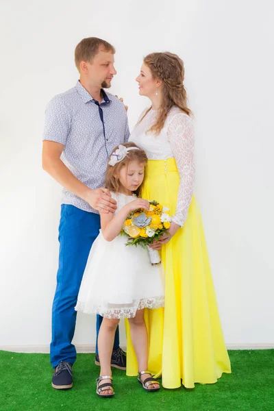 Young happy family with one child, in full growth. mom, dad, girl with a bouquet — Stock Photo, Image