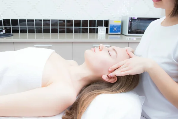 Cosmetologo fa massaggio facciale a giovane bella donna in spa — Foto Stock