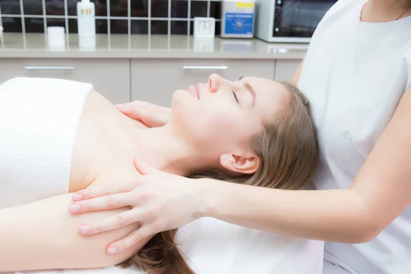 Cosmetologo fa massaggio facciale a giovane bella donna in spa — Foto Stock