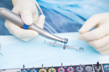 Yakın çekim diş implant diş hekimi elinde. Bir implantasyonu ameliyatı devam ediyor.