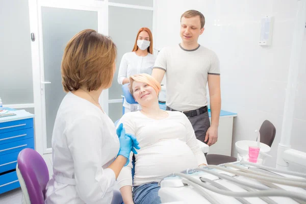 Zwangere vrouw bij de receptie bij de tandarts, de man zijn aanwezig in het kantoor. Tandheelkundige behandeling voor zwangere vrouwen. — Stockfoto