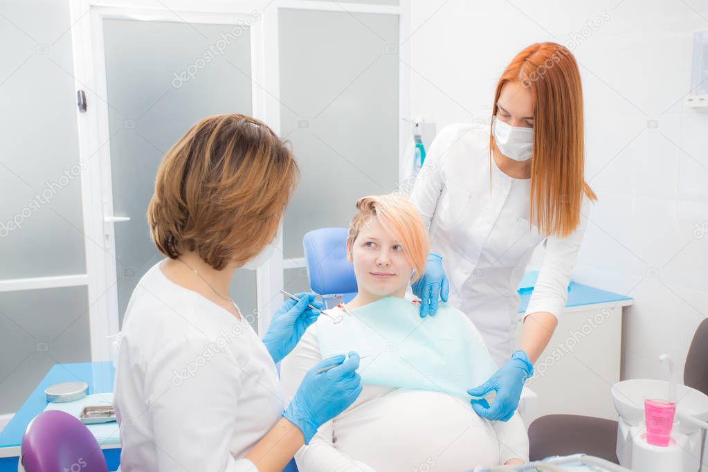 woman in the dentist's chair, the doctor adjusts the patient's head, the dental assistant