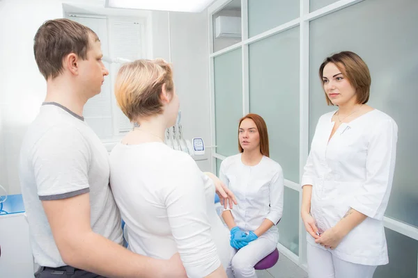 Zwangere vrouw en haar man communiceren met twee jonge vrouwen Tandartsen in een medisch kantoor. Tandheelkundige behandeling voor zwangere vrouwen — Stockfoto