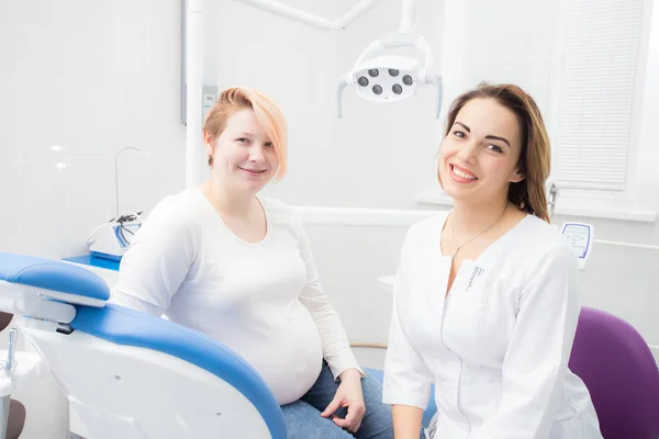 Mujer embarazada positiva en el consultorio del dentista, consulta con la joven dentista. tratamiento dental para mujeres embarazadas —  Fotos de Stock