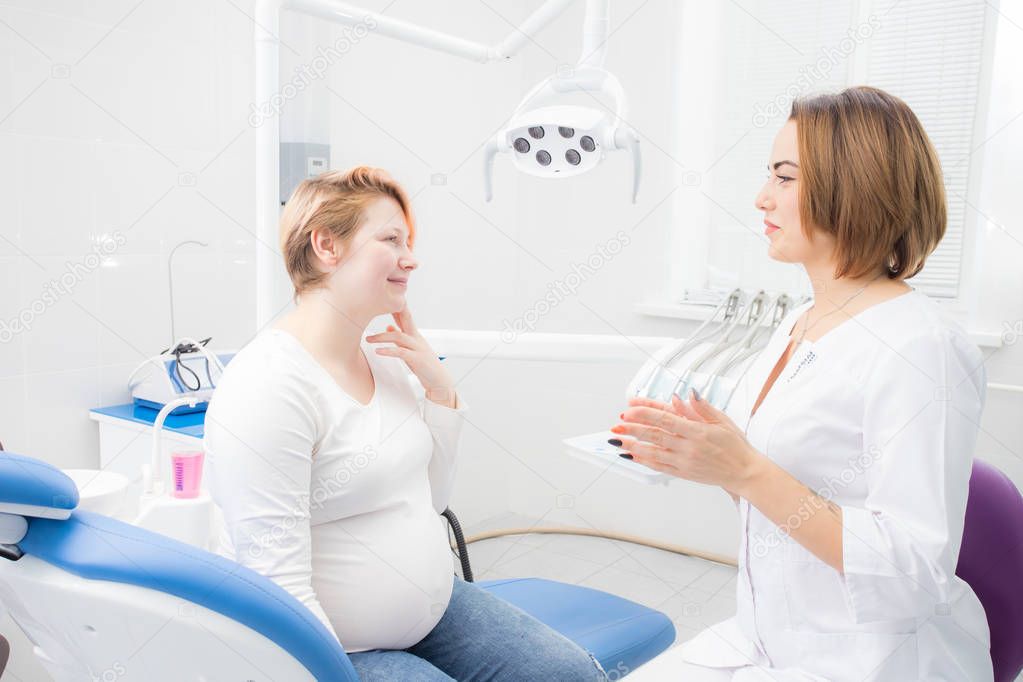 positive pregnant woman in dentist office, consultation with young woman dentist. dental treatment for pregnant women