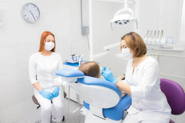 A female dentist and her assistant treat a little girl's teeth — Stock Photo, Image