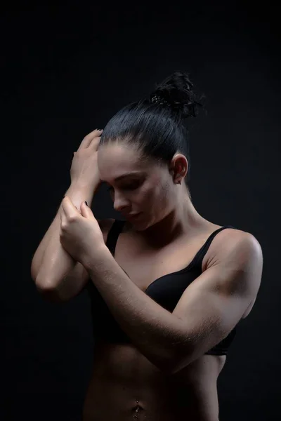 Portret van een jonge Sportvrouw van atletische bouwen in een badpak. Thema sport en bodybuilding. Vrouw op een zwarte achtergrond — Stockfoto
