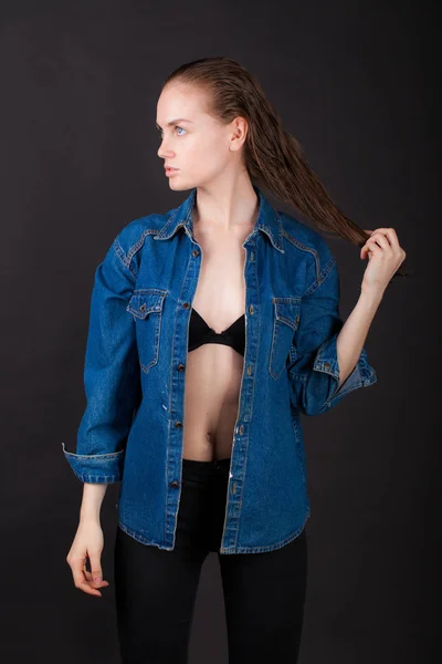 studio portrait of a very thin young woman in lingerie with wet hair and jeans jacket