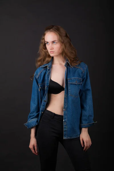 studio portrait of a very thin young woman in lingerie with wet hair and jeans jacket