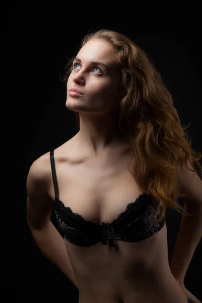 Portrait of a young, athletic and sexy woman in black underwear on a black background — Stock Photo, Image