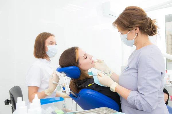 Mujer dentista trata un diente a una mujer — Foto de Stock