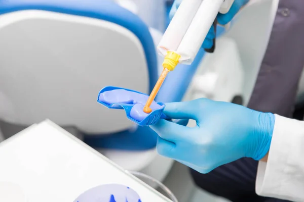 Diş hekimi diş kalıbı için malzeme hazırlar. Mavi eldivenli bir diş hekiminin yakın çekim — Stok fotoğraf