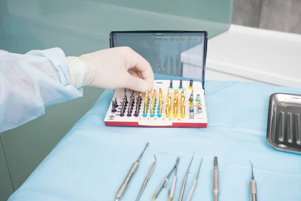 A mão do dentista leva o equipamento odontológico obstrutivo endodôntico no consultório do dentista — Fotografia de Stock