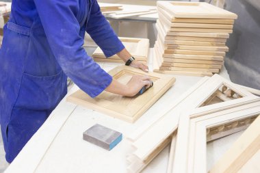 Çalışkan kadın marangoz atölyede ahşap zımparalıyor.