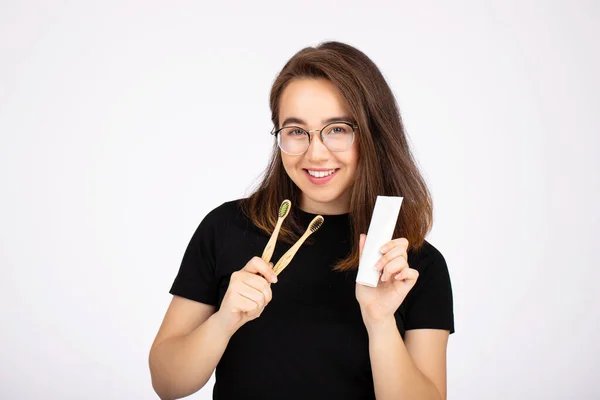 Positive Frau lächelnd mit Zahnbürste und Tube Zahnpasta isoliert auf weiß — Stockfoto