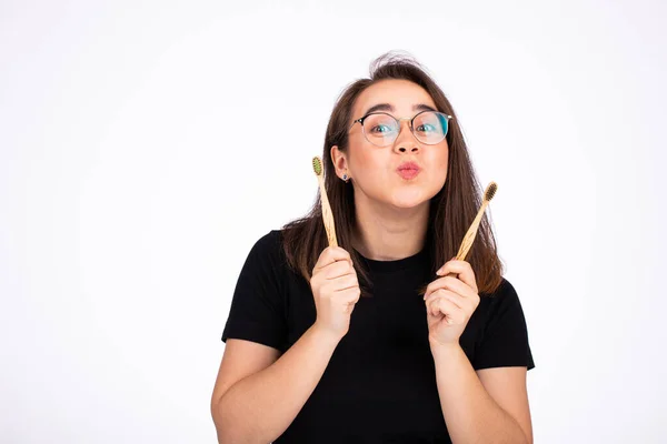 Porträt einer jungen schönen Frau mit Brille, die zwei Zahnbürsten isoliert auf weiß hält — Stockfoto