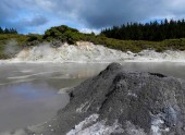 Malé Bahenní sopka stojící v kouřící fondu v Hells Gate, Nový Zéland