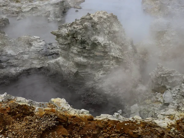 Steam coming out of a rock with orange mineral deposit