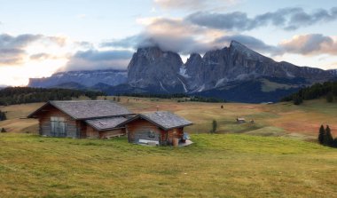 İtalya, Alpe di Siusi 'den güzel bir manzara. Yaz güneşinin doğuşunda küçük ahşap kulübesi ve keskin dolomit dağlarıyla. Seiser Sadm ve Langkofel Grubu Güney Tyrol, İtalya