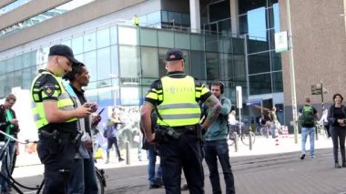 Hollanda polisi, Hollanda 'nın Lahey kentinde düzenlenen tecrit karşıtı bir protesto sırasında geçen bir kişinin kimlik kartını kontrol ediyor
