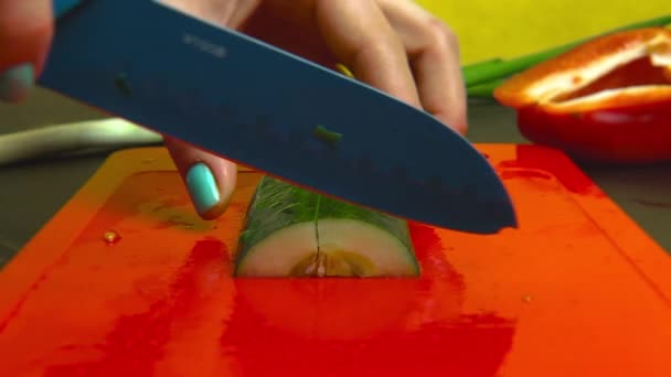 Een Meisje Met Een Kleur Manicure Snijdt Een Groene Komkommer — Stockvideo