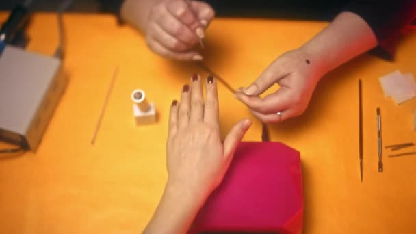 女の子は 乾燥ゲル マニキュアのピンクのランプで彼女の手を置きます 黄色のテーブルでは 美容業界をマニキュアします — ストック動画
