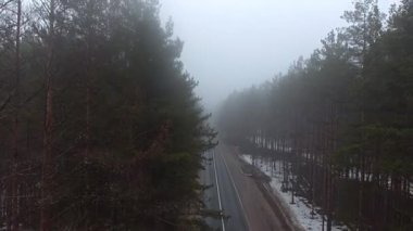 Sabah bulutlu, bir quadcopter uzak bir orman yolu üzerinde sis ağaçlardan uçan, araba geçen. Drone, helikopter