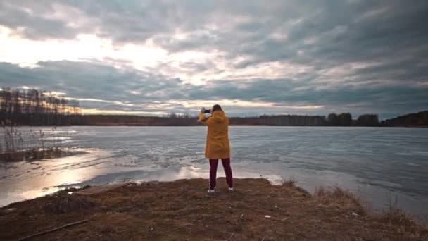 Woman Yellow Jacket Stands Bank Frozen Lake Spring Windy She — 비디오